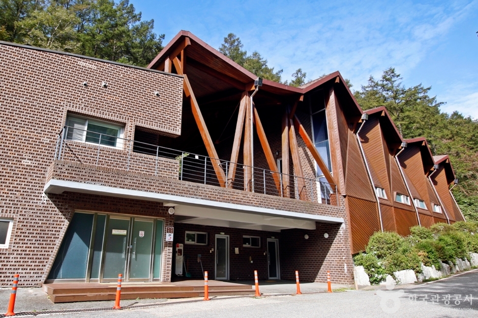 산비탈을 따라 길게 이어진 붉은 벽돌과 목재 트러스 외관의 국립덕유산자연휴양림 숙박동