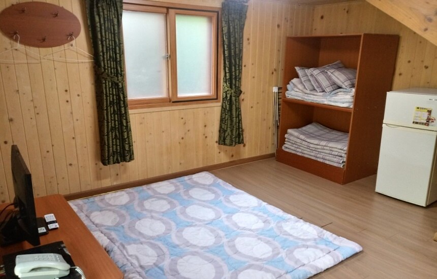 701호 (다락형). 2단지 – 창 아래 바닥 침구와 이불장, 냉장고·TV가 보입니다.